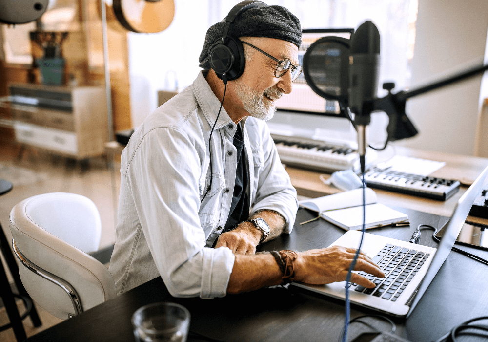 senior man in front of his laptop with headphones on podcasts for seniors