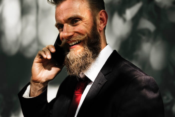 有胡子的人谈话在电话长途关系