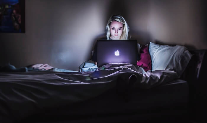 卧室里的Mac电脑上的女人社交媒体和人际关系