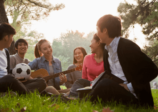 group sitting on grass singing songs get to know you questions