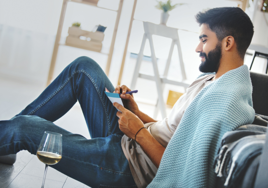 man sitting on sofa writing with pen and paper How to Write a Love Letter