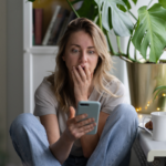 woman looking at phone while covering mouth with hand when stop reaching out to a friend