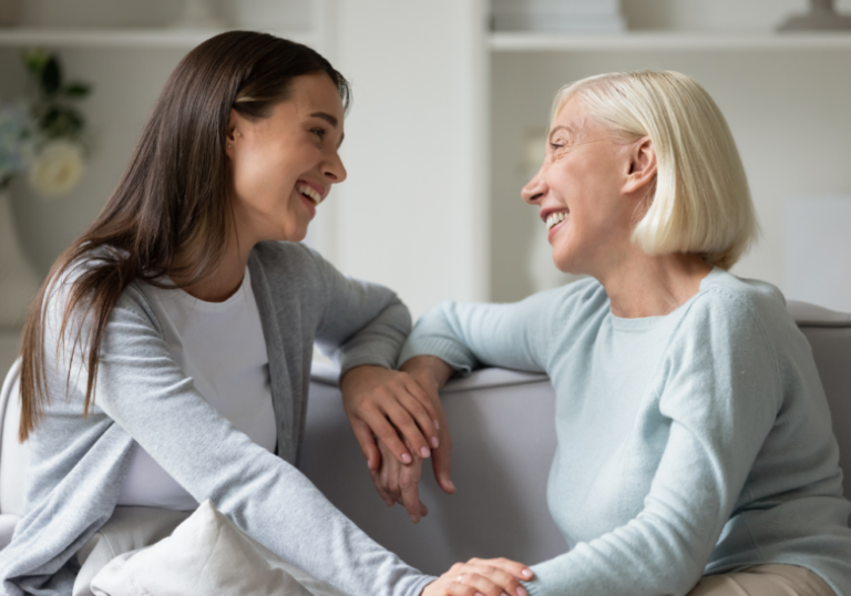 mother and daughter smiling at each other while sitting at the couch questions to ask your mom