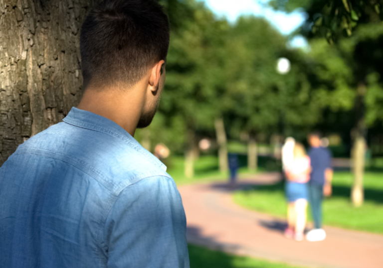 man hiding behind the tree watching someone when a narcissist sees you have moved on