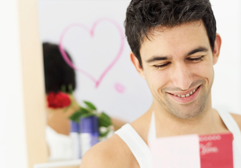 man looking at phone smiling wide anniversary messages to your boyfriend