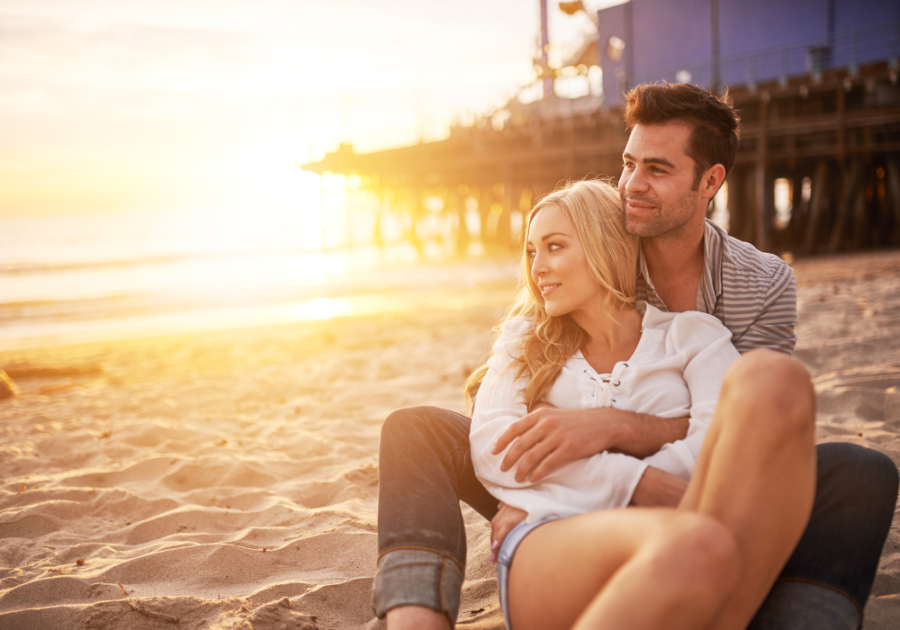 couple hugging sitting on beach Couples’ Birthday Ideas