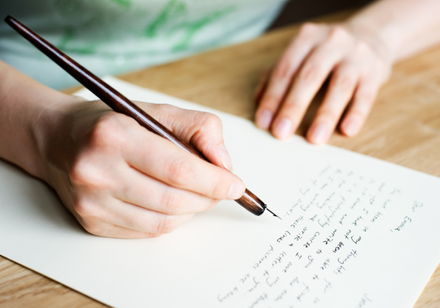 person's hand holding pen and writing Goodbye Letter to Lover