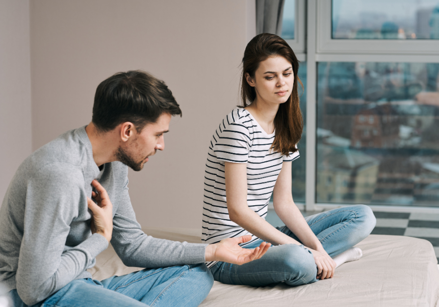 couple sitting on bed talking Signs That Your Girlfriend Isn't Sexually Attracted to You 