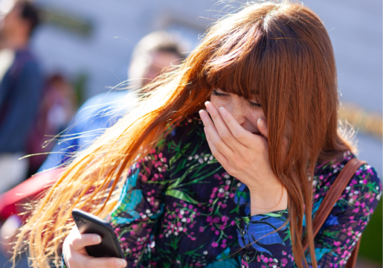 woman laughing while looking at phone Best Tinder Bios for Guys