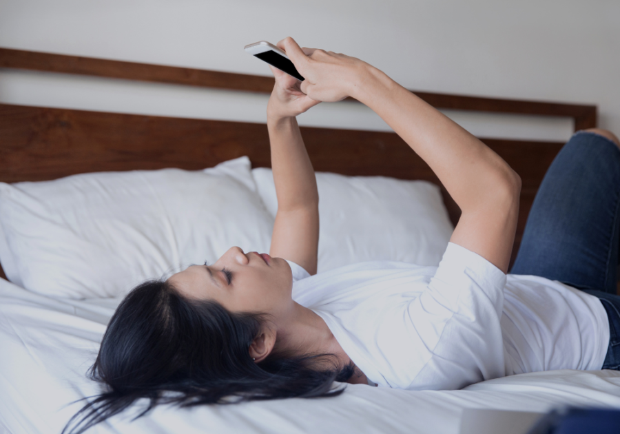 woman laying on bed looking at phone start a conversation on Tinder