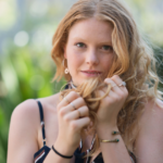 close up of woman holding her long hair what does it mean when she touches her hair when she sees you?