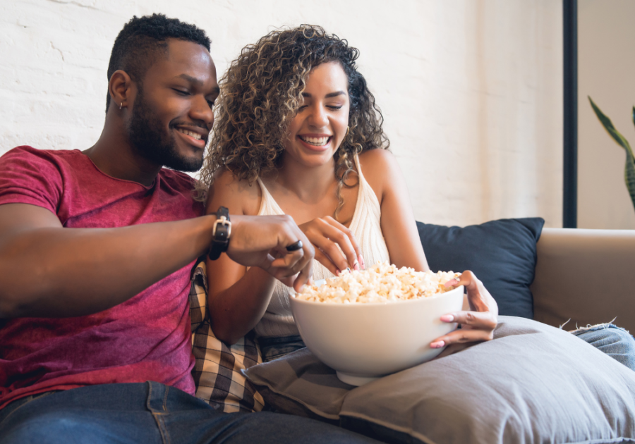 couple sitting on sofa Best Movies to Watch with Your Boyfriend