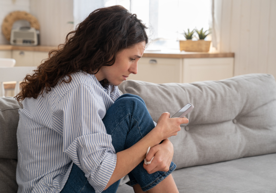 woman sitting on sofa looking at phone How To Tell Someone You Just Want To Be Friends