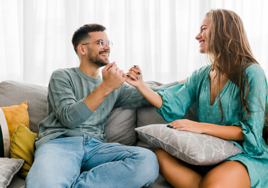 couple holding hands smiling on sofa compromise in a relationship