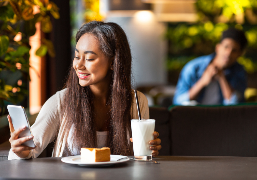 woman in restaurant smiling looking at phone Hinge Profile Tips