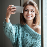 woman smiling taking a selfie with phone Hinge Profile Tips