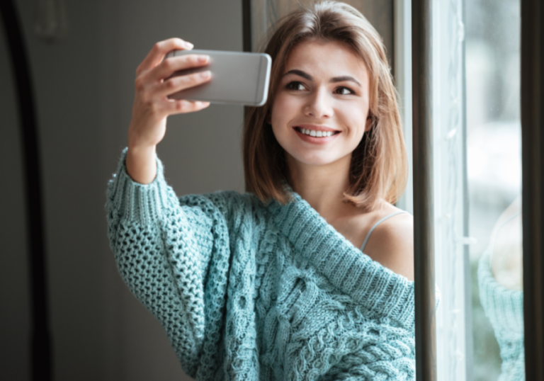 woman smiling taking a selfie with phone Hinge Profile Tips