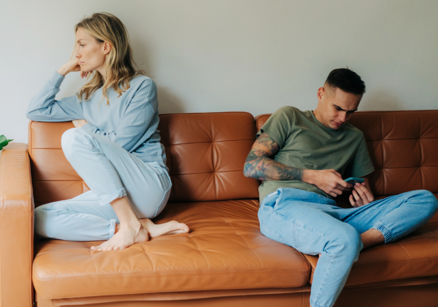 man texting on sofa woman is turned away Signs Your Boyfriend Likes His Female Friend