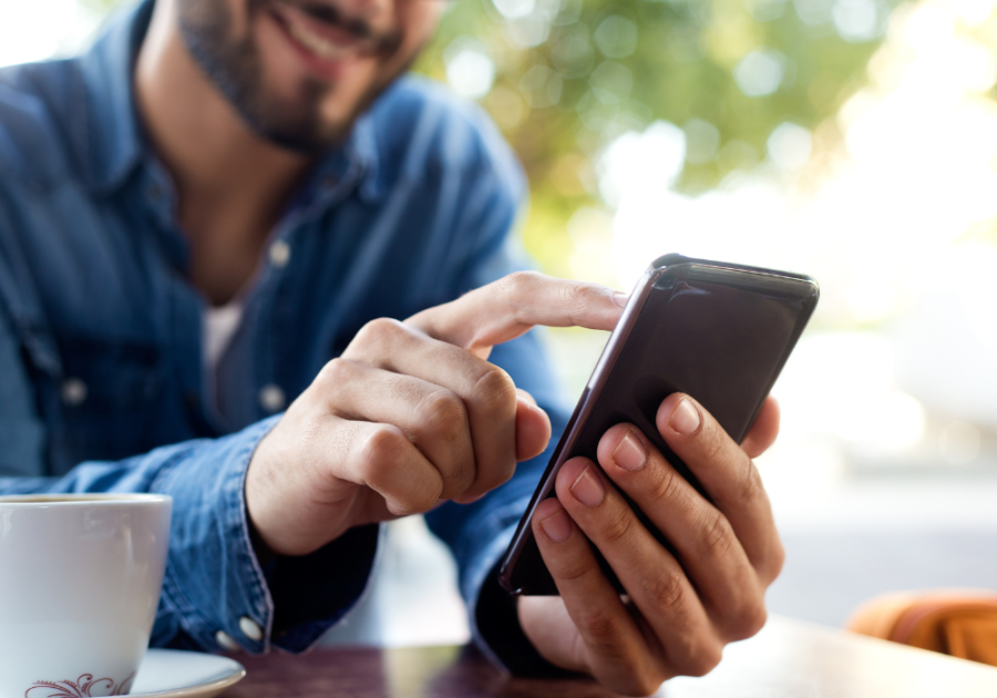 man having coffee texting on phone Hinge Profile Tips