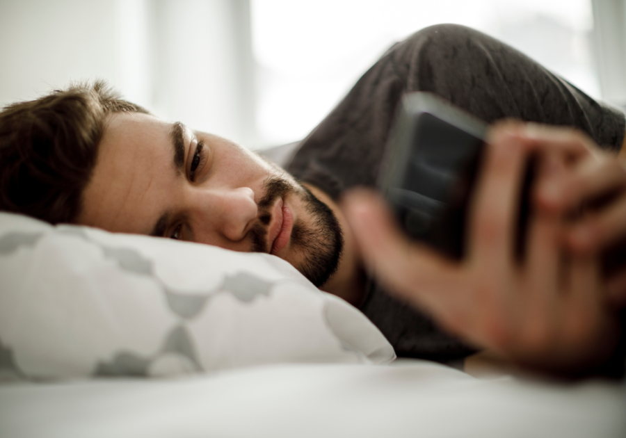 man in bed looking at phone did he block you because he cares