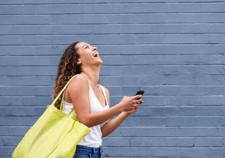woman walking by ocean with phone laughing Truth or Dare Over Text