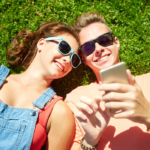 couple laying on grass looking at phone dating apps for teenagers