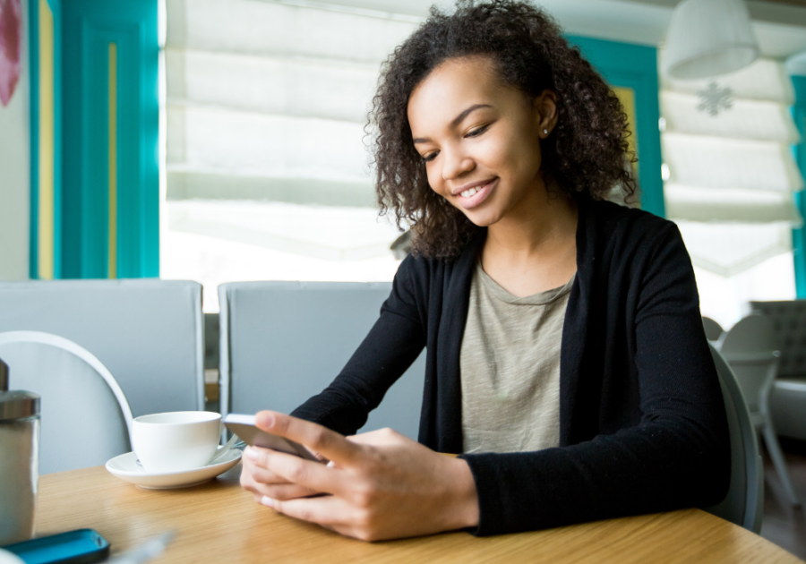 woman sitting at table looking at phone Tinder Bios for Women