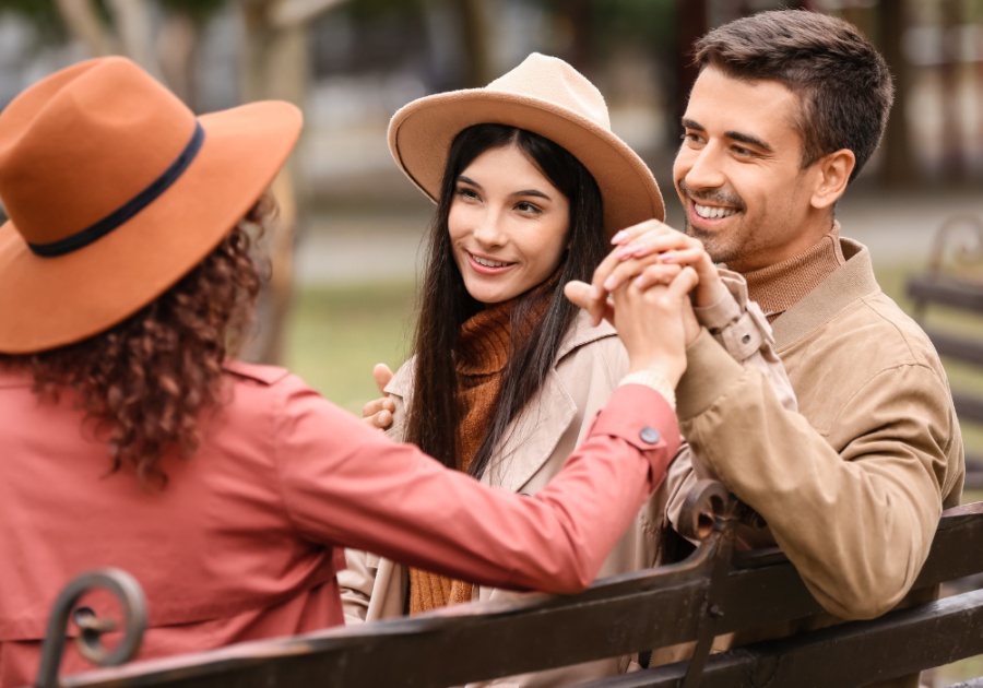 two women and man sitting on bench unicorn relationship