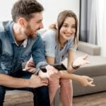 couple sitting on sofa laughing Signs a Sagittarius Man Has Feelings for You