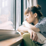 woman staring out window Signs You Will Never Find Love