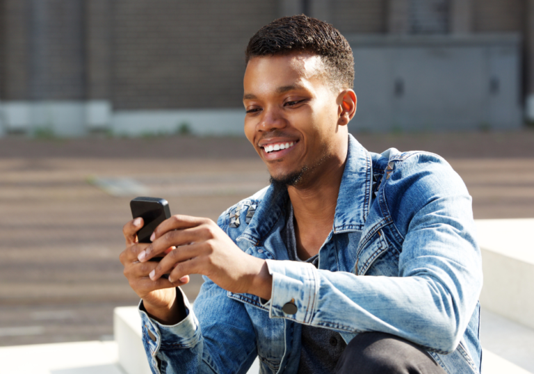 man smiling looking at phone Interesting Questions to Ask a Girl Over Text 