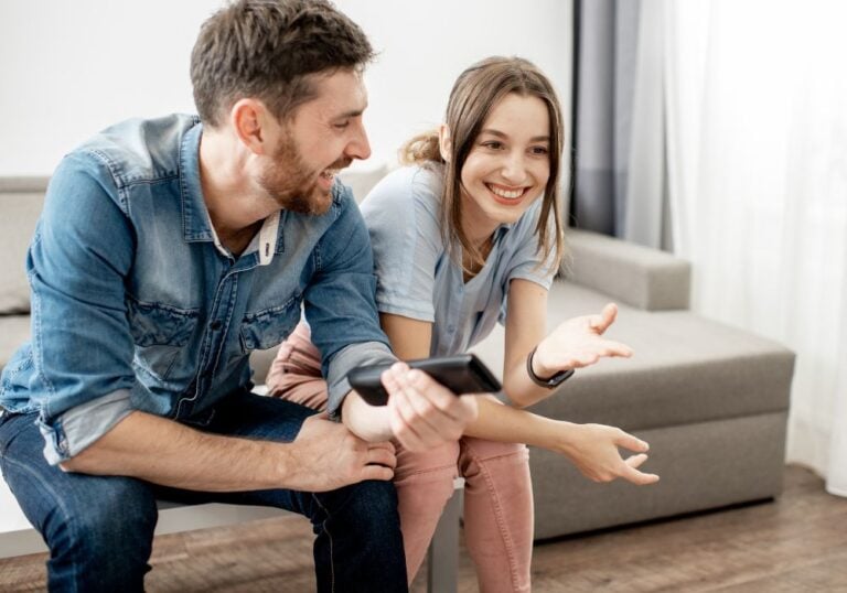 couple sitting on sofa laughing Signs a Sagittarius Man Has Feelings for You