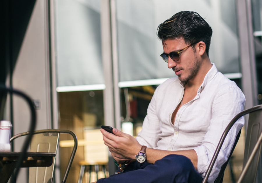 man sitting outside looking at phone Interesting Questions to Ask a Girl Over Text 