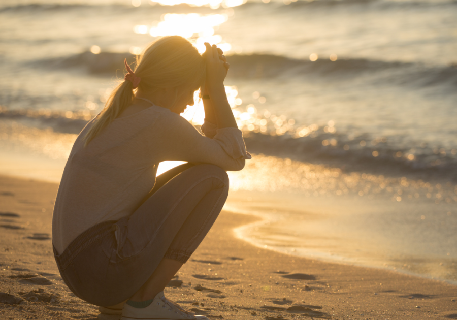 woman sitting on beach at sunset Songs About Unrequited Love