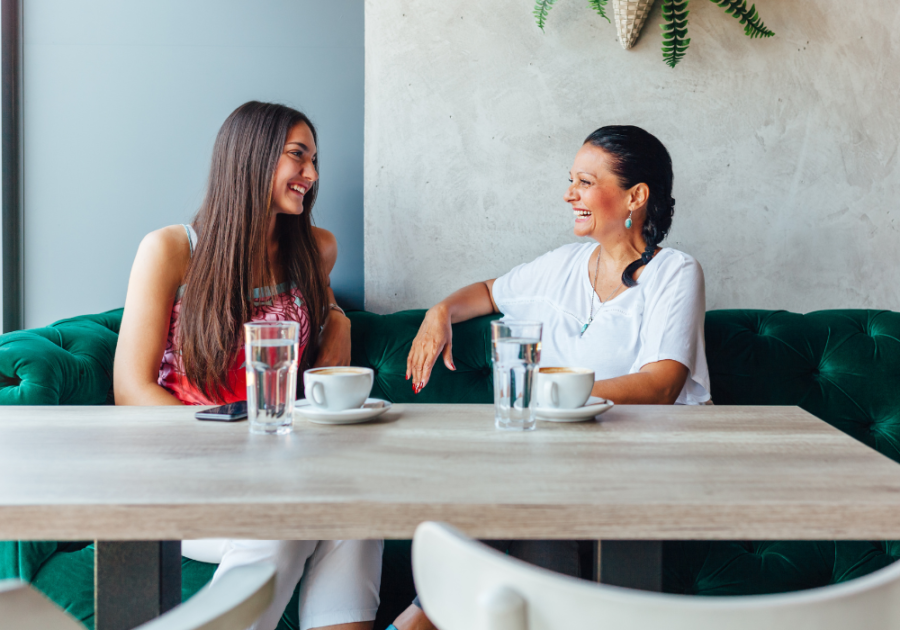 two women sitting at table smiling Symptoms of Bisexuality in Females