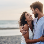 couple at ocean hugging smiling what do men find attractive in women