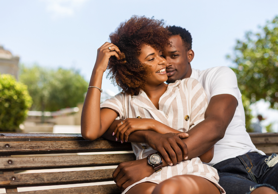 man hugging woman from behind on park bench Signs He Wants You Badly Sexually