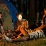 friends camping sitting by fire at night scary games to play with friends