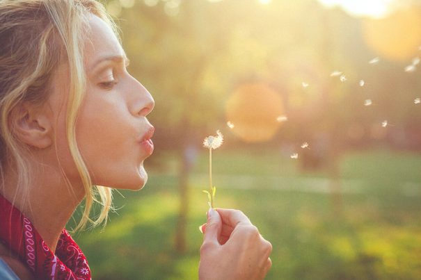 Woman blowing dandelion, key to happiness