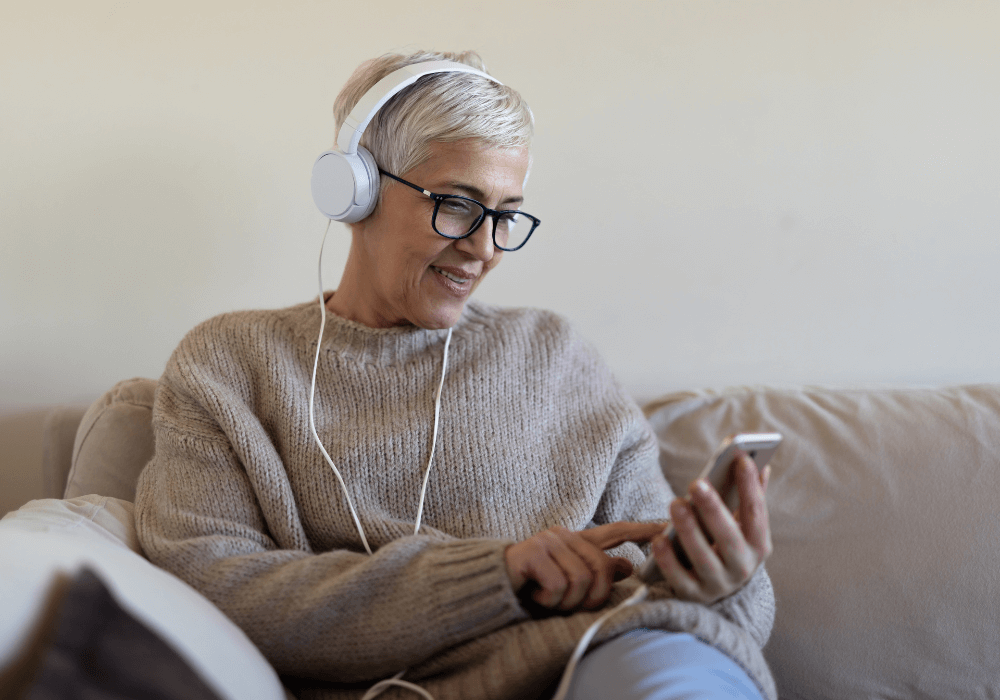 senior woman browsing her phone with headphones on best ways to listen to music